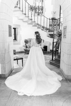 a woman in a wedding dress is walking down the stairs with her back to the camera