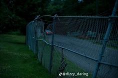 a fence with barbed wire on the side of it at night, next to a road