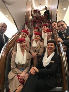 a group of people that are sitting down on an airplane stairs with headscarves