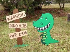 a dinosaur standing next to a wooden sign that says warning dino - mite party ahead