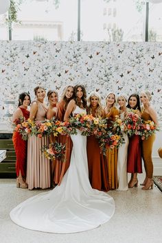 a group of women standing next to each other in front of a wall with flowers