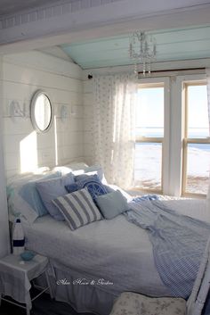 a white bed sitting next to a window in a bedroom under a chandelier