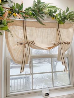 the window is decorated with greenery and ribbon tied around the valance, along with two bow tie sashes