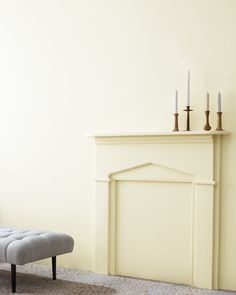 a living room with a white fireplace and two candles on top of the mantel