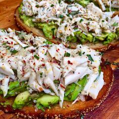 two pieces of bread topped with chicken and cucumber on top of a wooden cutting board