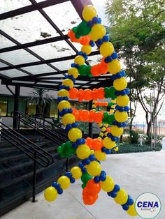 a bunch of balloons that are hanging from a ceiling in front of some stairs and trees