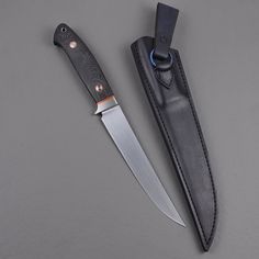 a knife and sheath on a gray surface