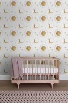 a baby's crib in front of a wall with gold stars and crescents on it