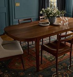 a dining room table and chairs in front of a window with blue paint on the walls