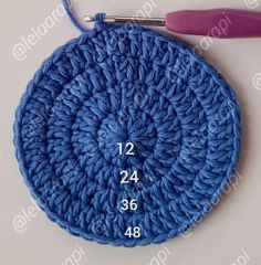 a crocheted blue circle with the number twenty four on it, next to a pair of scissors