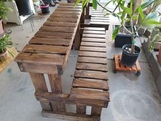 a wooden bench sitting next to a potted plant on top of a cement floor