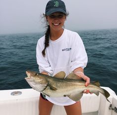 a woman holding a fish on the back of a boat