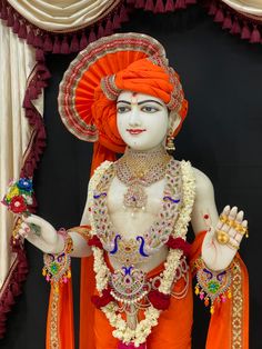 a statue of a woman in an orange outfit with jewelry on her head and hands