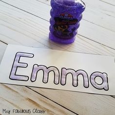 an empty name tag sitting on top of a wooden table next to a purple bottle