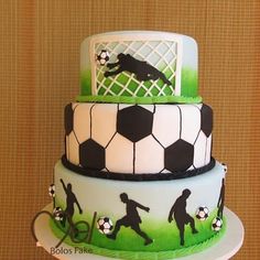 a three tiered cake with soccer themed frosting on it's sides and the silhouettes of people playing soccer