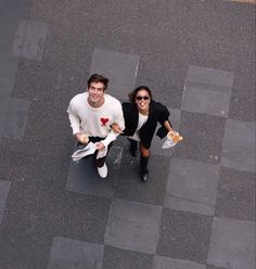 two people walking down the street with food in their hands