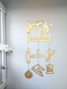 a metal wall hanging with scissors and other items on it's side, next to a window