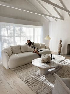 a woman sitting on top of a couch in a living room next to a table