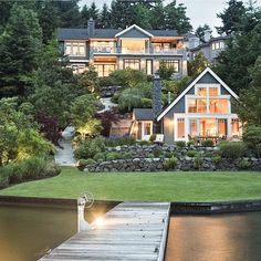 a large house sitting on top of a lush green hillside next to a lake at night