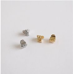 three pairs of gold and silver cufflinks on a white surface, one has a square clasp