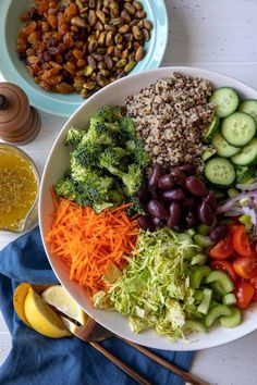 a white plate topped with lots of veggies next to a bowl of beans