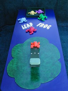 a blue table topped with paper cutouts and animals on top of it, next to a game board