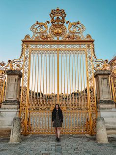 a woman standing in front of a golden gate with ornate carvings on the top and sides