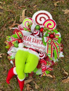 a christmas wreath with candy canes and an elf's hat on it in the grass