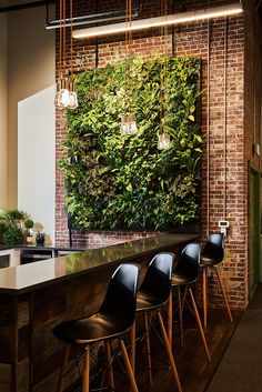 a bar with black chairs and a green wall behind it