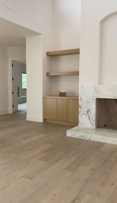 an empty living room with white walls and wood floors, fireplace built into the wall