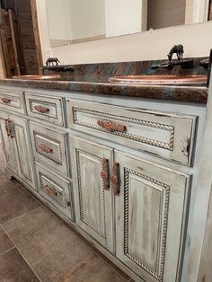 an old bathroom vanity with marble top and metal pulls on the drawers, in front of a large mirror