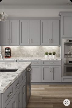 a kitchen with gray cabinets and marble counter tops