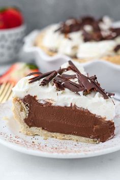 a slice of chocolate cream pie on a white plate with strawberries in the background