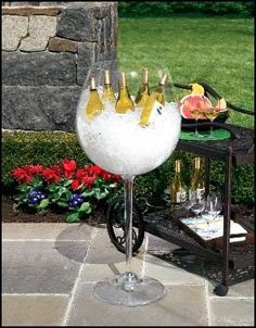 a wine glass sitting on top of a table next to a flower pot and vase