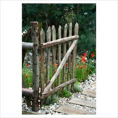 an old wooden gate is in the middle of some rocks and flowers with red poppies