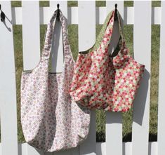 two purses hanging on the side of a white fence