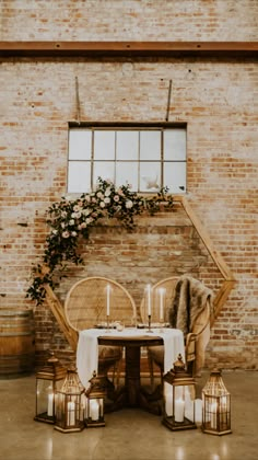 a table with candles and flowers on it in front of a brick wall