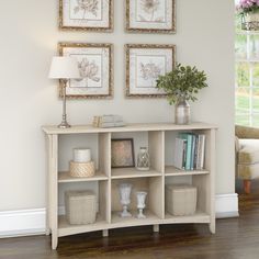 a white shelf with baskets and vases on it in front of a wall display