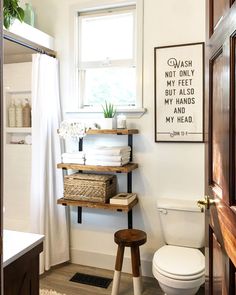 a white toilet sitting next to a wooden shelf filled with towels and other bathroom items