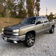 a silver truck parked on top of a gravel road