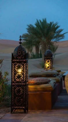 two lamps sitting on top of a wooden bench in the middle of a desert area