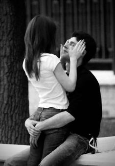 a man and woman sitting next to each other on a bench in front of a tree