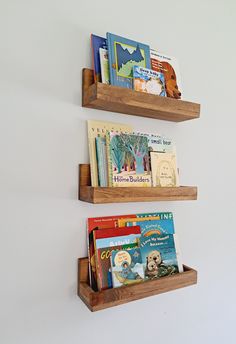 two wooden bookshelves with children's books on them against a white wall