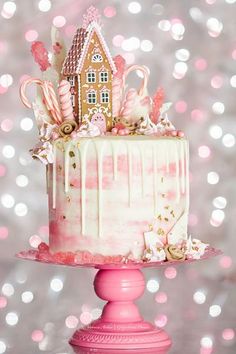 a pink and white cake decorated with candy canes, candies, gingerbread houses and lollipops