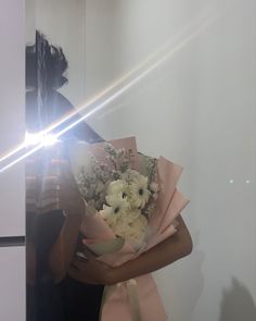 a woman holding a bouquet of flowers in front of her face with the light shining through