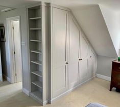 an attic bedroom with built - in closets and white painted walls, carpeted flooring