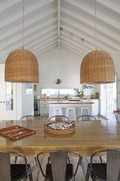 a large wooden table with four chairs around it and two hanging baskets on the ceiling