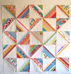 a quilted wall hanging on the side of a wall with different colored strips in it