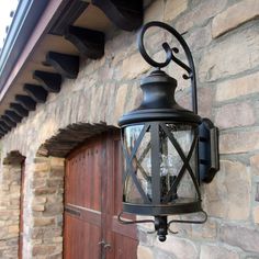 an old fashioned light hanging on the side of a stone building next to a wooden door