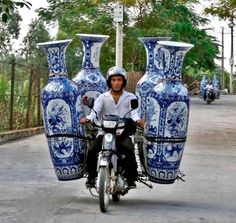 a man riding on the back of a motorcycle next to blue vases